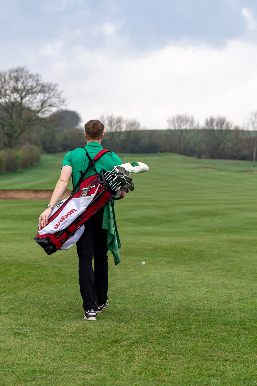 Person walking on a golf course with a golf bag